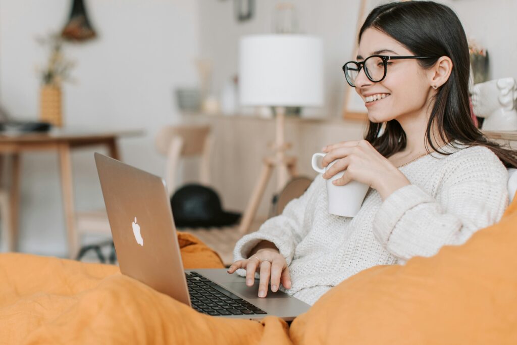 Woman enjoying a cozy moment with a laptop and coffee in a modern interior setting.